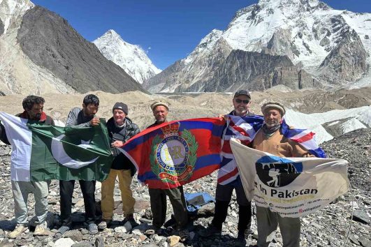 K2 Base Camp trekking. Group is at Concordia raising flag and backdrop is K2