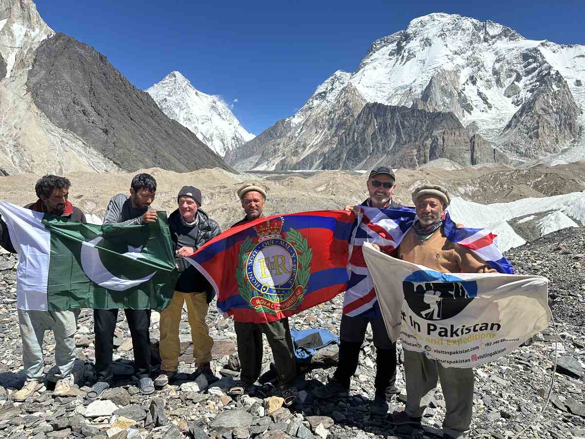 K2 Base Camp trekking. Group is at Concordia raising flag and backdrop is K2